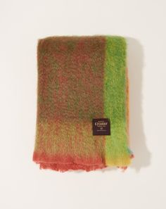 a multicolored scarf with a tag on the front and back of it, sitting on a white surface