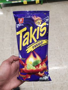 a hand holding up a bag of taki's fuggie on the floor