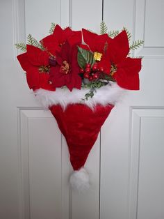 a christmas decoration hanging on the front door with poinsettis and greenery