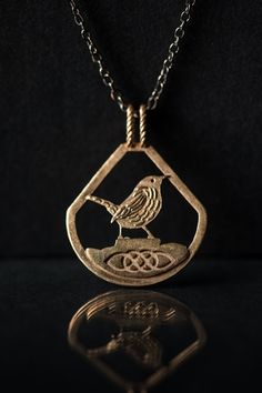 a bird sitting on top of a metal object in the shape of a tear shaped pendant