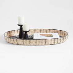 a wicker tray with two white candles on it and a magazine in the middle