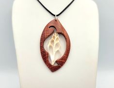 This is a unique totally hand carved wooden necklace which showcases an astonishing seashell gastropod. This piece of jewelry is made of a red coloured beech wood and it is one of a kind. It hangs from a black cord.  The artist of this pendant is Nikos Bacharidis who was born in 1946 and he is a Greek artist, sculptor, painter and engraver. Today he lives in Thessaloniki and he focuses on sculpture, abstract organic forms and nature inspired designs. Since 1971 he has participated in more than 8 Carved Necklace, Hand Carved Jewelry, Sculpture Abstract, Seashell Jewelry, Organic Forms, Beauty Cream, Wooden Necklace, Seashell Necklace, Wire Work Jewelry