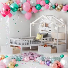 a room with balloons and confetti all over the floor, including a doll house bed