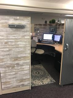 an office cubicle with two computers on the desk