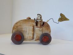 an old fashioned toy car with a man in the driver's seat and a kite flying above it