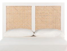 a bed with two pillows on top of it next to a headboard made out of wicker