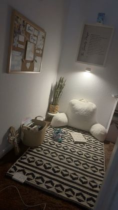 a white teddy bear sitting on top of a rug next to a potted plant