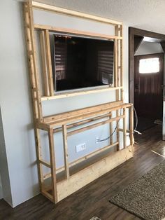 a living room with a tv mounted on the wall and wood flooring in front of it