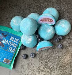 blue matcha tea balls are on the ground next to some blueberries and a bag of blueberries