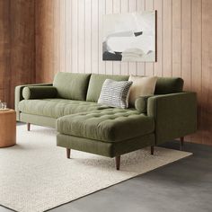 a green couch sitting on top of a rug in a living room next to a wooden wall