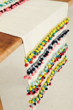 a wooden table topped with a white table cloth covered in multicolored beads