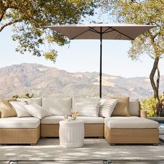 an outdoor couch with pillows and umbrella over it