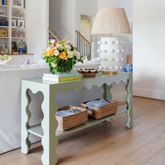 a living room with a couch, coffee table and flowers on the end table in front of it