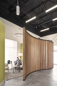 a man sitting in a chair next to a wooden partition