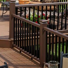 a bird sitting on the ground next to a railing and table with flowers in it