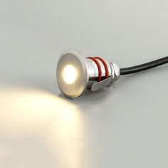 a close up of a light on a white surface with a black cord attached to it