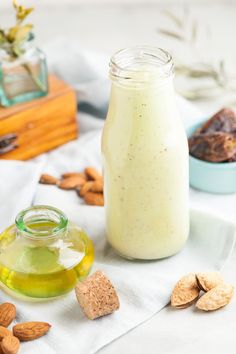 a jar filled with almonds next to a bowl of nuts on a white towel