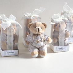 three small teddy bears in clear boxes with ribbons