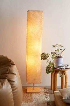 a lamp that is on top of a table next to a chair and potted plant