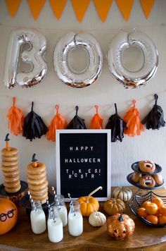 a table topped with lots of halloween treats and balloons in the shape of boos