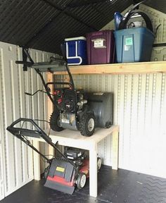 the inside of a storage shed with two lawn mowers and other items on it