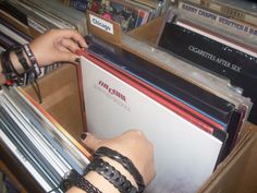 a person is holding up some records in a box on top of other recordshelves