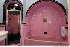 a pink bath tub sitting next to a white sink in a bathroom under two mirrors