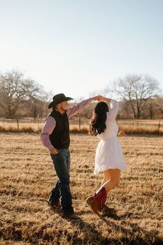 a man and woman dancing in an open field