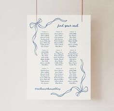 a blue and white wedding seating chart hanging on a wall with twine ribbons attached to it