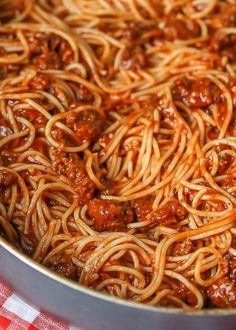 spaghetti with meat sauce in a pan on a red and white checkered tablecloth