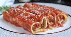 two pieces of lasagna on a plate with parmesan cheese and tomato sauce