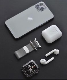 an apple watch, earbuds, and accessories laid out on a black surface