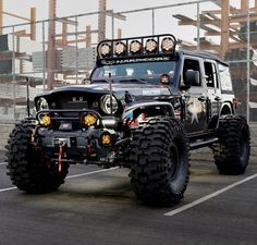 a black jeep with lights on driving down the street