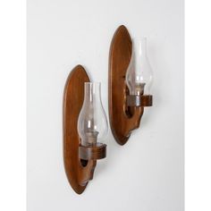 two glass vases are mounted on wooden wall sconces, one is clear and the other is brown