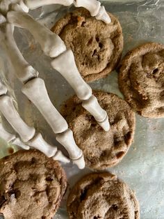 skeleton hands holding cookies on top of a baking sheet covered in frosted icing