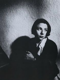 a black and white photo of a woman leaning against a wall