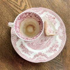 a cup and saucer with a piece of bread in it on a wooden table