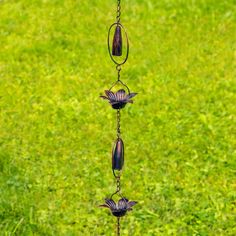 a wind chime hanging from a chain on top of a green grass covered field