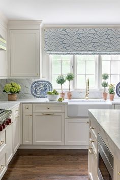 a white kitchen with blue and white decor on the window sill above the sink