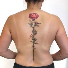 a woman's back with a pink flower tattoo on her left side ribcage