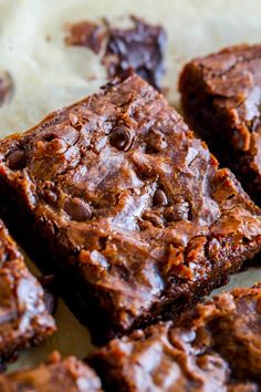 chocolate brownies cut into squares sitting on top of a piece of parchmented paper