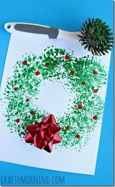 a paper christmas wreath with red bows and green sprinkles on it next to a sharp knife