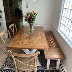 a wooden table sitting in the middle of a living room next to a vase with flowers