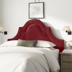 a red headboard on a white bed in a room with two nightstands and lamps