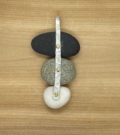 "Three tiered beach pebble pendant. The largest stone is basalt, the second is a grey pebble and the last and smallest, is white quartz. The pendant is held together with hand hammered sterling silver bail and fastened with two brass rivets.  The combination of these three stones together create a beautiful pendant that can be dressed up with layering up with other pendants or as a standalone. Two 30\" chain selections, a sterling silver rolo chain and a stainless-steel cable chain; see add on o Sea Pottery Jewelry, Beach Multi-strand Jewelry With Natural Stones, Beach Pebble Jewelry, Silver Sea Glass Jewelry For Beach, Sea Pottery Necklace, Silver Sea Glass Round Pendant Jewelry, Rivet Jewelry, Pebble Jewelry, Pebble Pendant