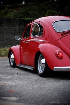 an old red vw bug parked in a parking lot