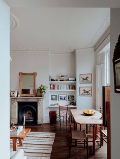 a living room filled with furniture and a fire place next to a table in front of a fireplace