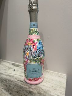 a bottle of pink wine sitting on top of a counter next to a white wall