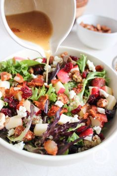 someone pouring dressing into a salad in a bowl