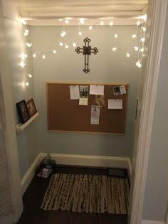 a bulletin board in the corner of a room with lights strung from it and pictures hanging on the wall